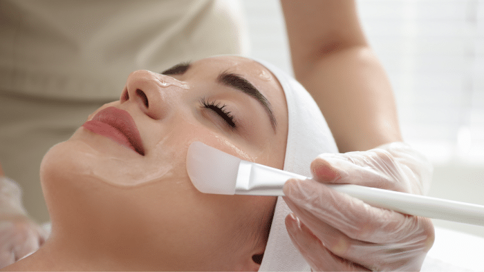 A skin specialist performing a chemical peel treatment session on an individual’s face.