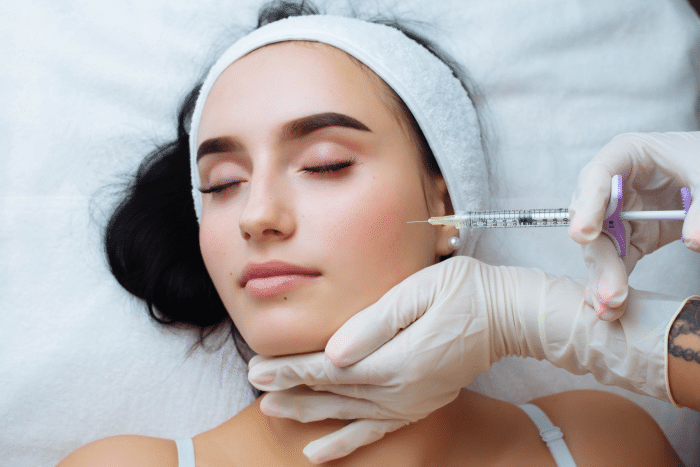 
A professional is administering a Juvederm filler treatment to a relaxed patient, demonstrating the cosmetic procedure aimed at enhancing facial features.