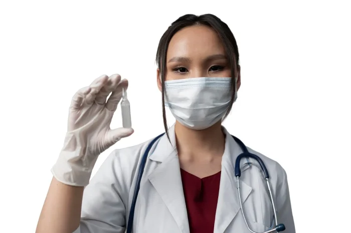 A doctor wearing a white coat, surgical mask, and gloves holds up a small vial used in the Lanluma protocol. A stethoscope hangs around her neck. The background is plain white.